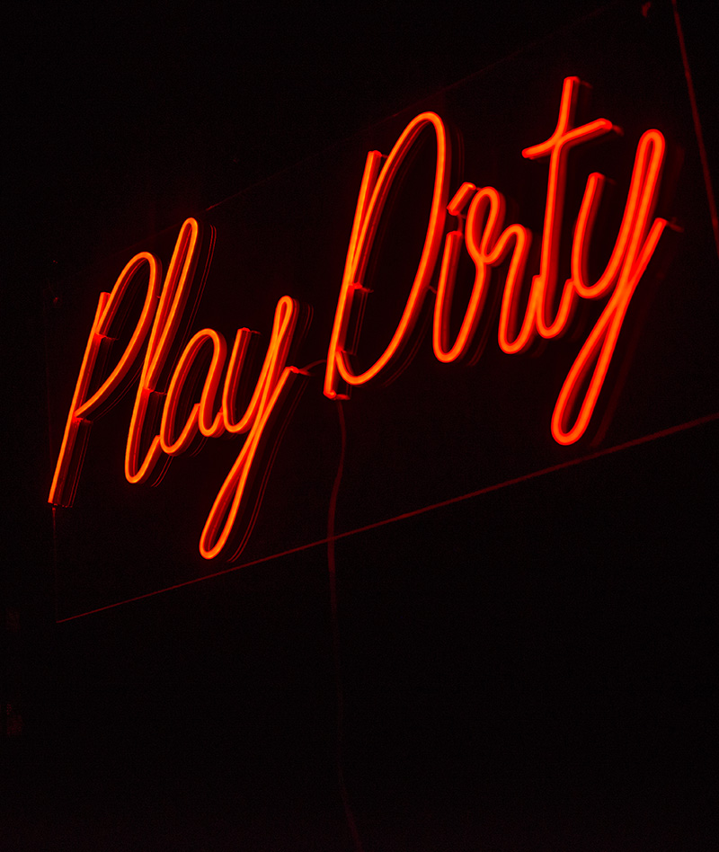 a neon sign that reads Play Dirty